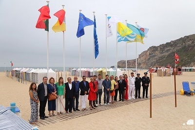 Imagem da praia da Nazaré com as Bandeiras hasteadas e todos os responsáveis presentes na cerimónia