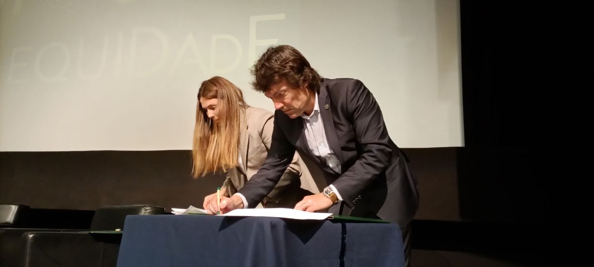 Sónia Esperto of the INR and António Barbosa of the Municipality of Monção are signing documents. A screen with projection is visible from behind.