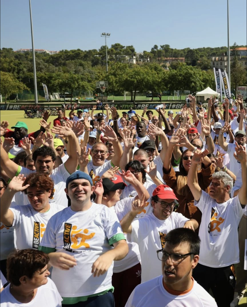 A large group of people gathered outdoors, all wearing white T-shirts with the 