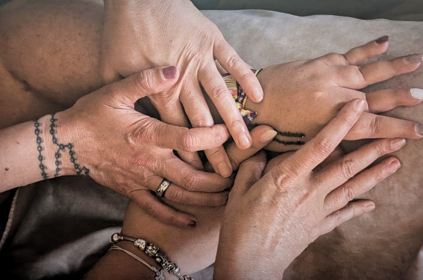  Fotografia de quatro mãos sobrepostas. 