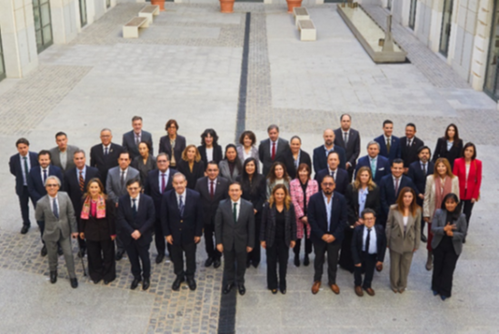  Fotografia de grupo com cerca de quarenta pessoas, mulheres e homens, em trajes formais, organizadas em várias filas num pátio exterior de um edifício institucional, a pousar para uma foto. Group photo with about forty people, women and men, in formal costumes, arranged in several rows in an outer courtyard of an institutional building, landing for a photo. 