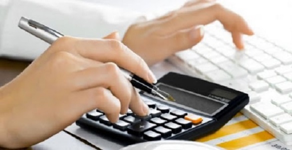 Mãos sobre teclado de computador e calculadora que seguram uma caneta na mão direita.