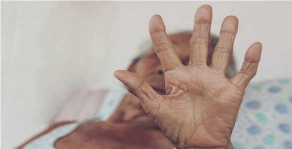 mão levantada de uma pessoa idosa que está deitada numa cama