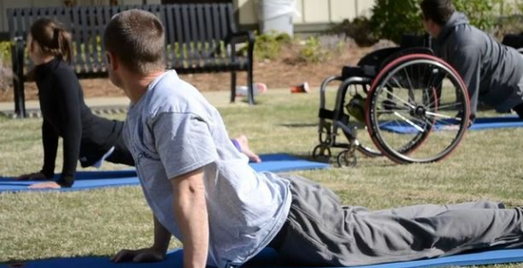 campo relvado com várias pessoas em tapetes de ioga.