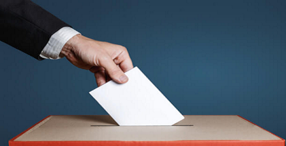 Uma mão a colocar um papel dobrado numa urna.