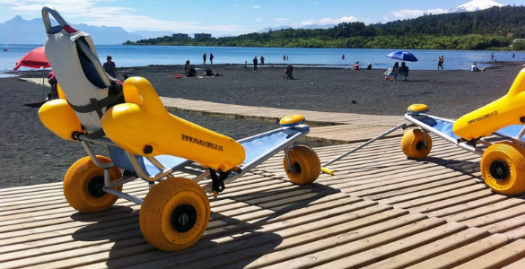 Grande plano de duas cadeiras anfíbias sobre passadiços de madeira até á água numa praia fluvial.