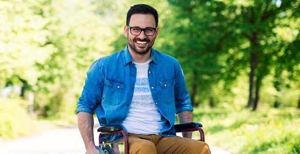 A young man in a wheelchair in a country setting.