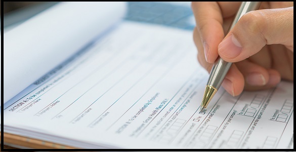 hand holding a ballpoint pen and filling out a sheet.