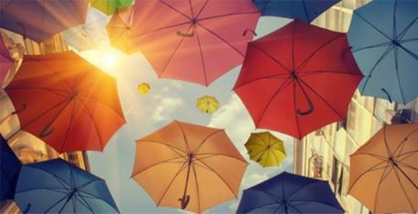 Imagem de um conjunto de guarda sois, de várias cores, abertos, numa perspetiva de baixo para cima.