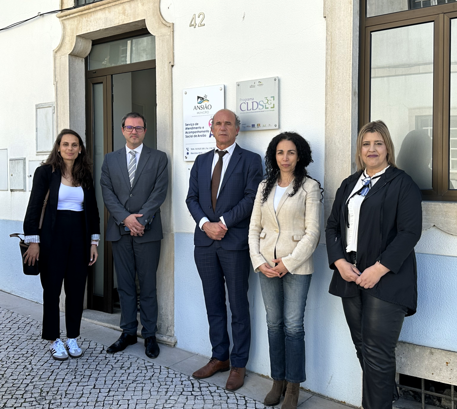 Na imagem é possível ver 5 pessoas em pé, em frente do edifício da Ação Social do Município de Ansião. As pessoas na imagem são: Gisela Afonso, técnica superior do INR, Rodrigo Ramos, Presidente do Conselho Diretivo do INR, António Domingues, Presidente da Câmara Municipal de Ansião, Paula Bernardino Vereadora do Município e Cristina Sá Interlocutora do BI de Ansião